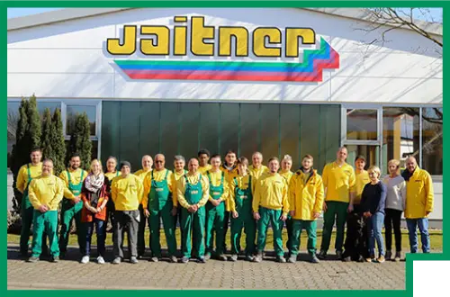 Eine Gruppenfoto von den Mitarbeitern von Jaitner. Sie lächeln und posieren fröhlich zusammen.